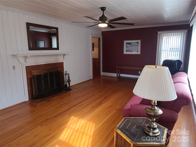 living room featuring crown molding, ceiling fan, hardwood / wood-style floors, and a brick fireplace