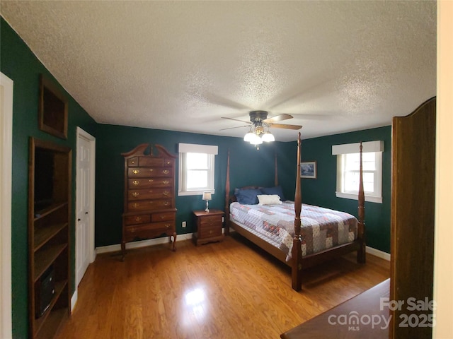 bedroom with hardwood / wood-style floors, a textured ceiling, and ceiling fan