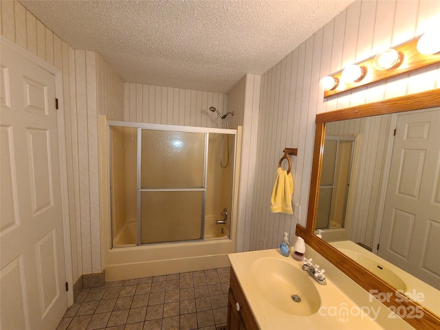 bathroom featuring vanity, bath / shower combo with glass door, tile patterned flooring, and a textured ceiling