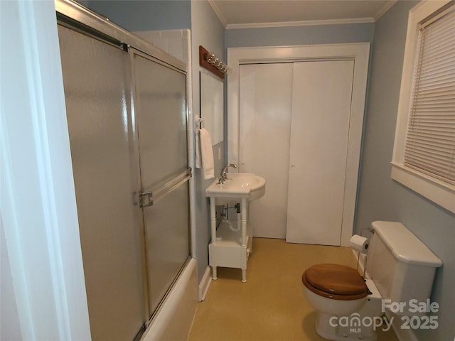 bathroom featuring crown molding, toilet, and combined bath / shower with glass door