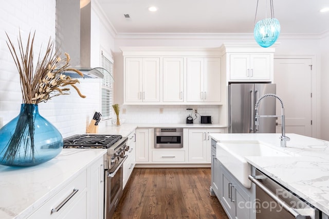 kitchen with appliances with stainless steel finishes, white cabinetry, ornamental molding, light stone counters, and wall chimney exhaust hood