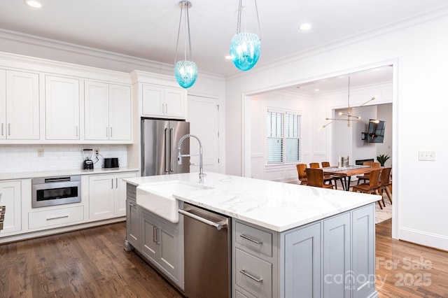 kitchen featuring decorative light fixtures, white cabinets, a kitchen island with sink, stainless steel appliances, and light stone countertops