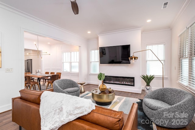 living room featuring hardwood / wood-style floors, crown molding, and a healthy amount of sunlight