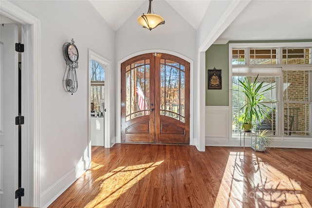 entrance foyer with wood-type flooring, vaulted ceiling, and french doors