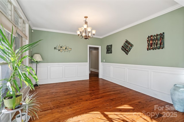 unfurnished room featuring dark hardwood / wood-style flooring, ornamental molding, and a chandelier