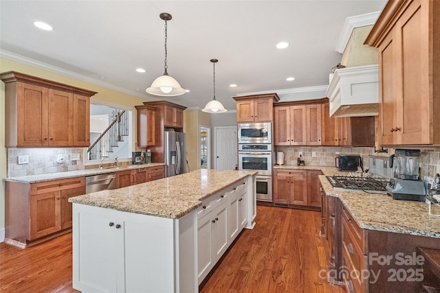 kitchen with white cabinetry, crown molding, decorative light fixtures, a center island, and appliances with stainless steel finishes