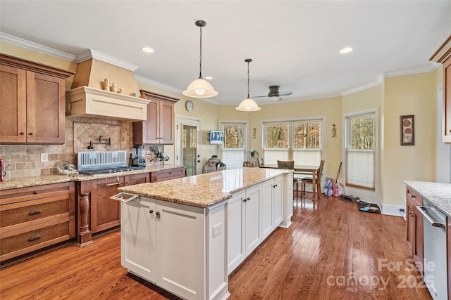 kitchen with pendant lighting, tasteful backsplash, white cabinetry, stainless steel dishwasher, and light wood-type flooring