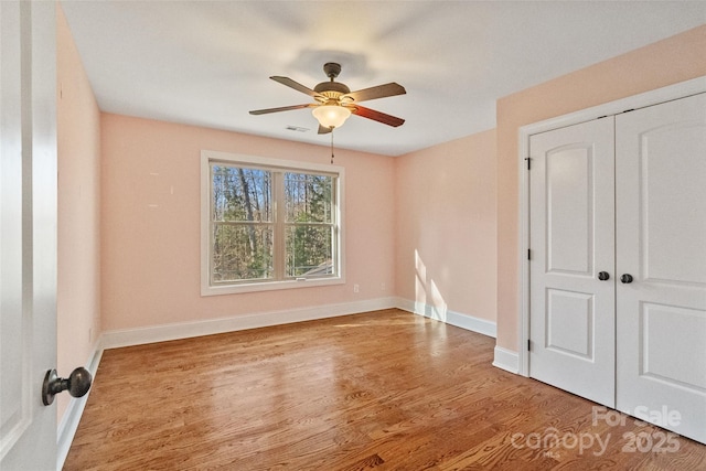 unfurnished bedroom featuring hardwood / wood-style floors, ceiling fan, and a closet