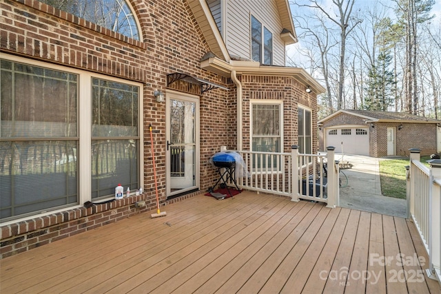 wooden terrace with an outbuilding, a grill, and a garage