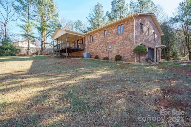 rear view of house featuring central AC unit, a garage, and a yard