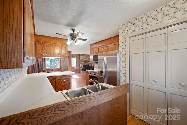 kitchen featuring sink, ceiling fan, stainless steel appliances, a textured ceiling, and kitchen peninsula