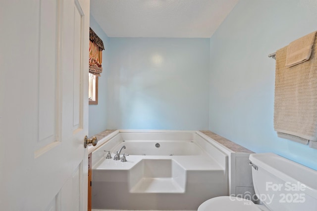 bathroom featuring toilet, a bath, and a textured ceiling