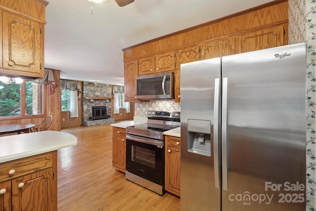 2076 Jay Clark Rd, Morganton, NC 28655 - kitchen featuring brown cabinetry, stainless steel appliances, a fireplace, light wood finished floors, and light countertops