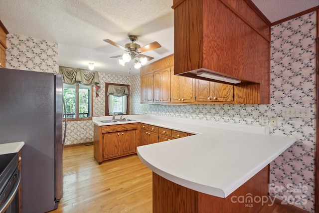 2076 Jay Clark Rd, Morganton, NC 28655 - kitchen with freestanding refrigerator, light wood-style flooring, wallpapered walls, ceiling fan, and a peninsula