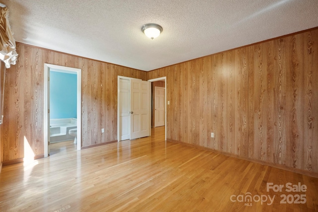 2076 Jay Clark Rd, Morganton, NC 28655 - unfurnished bedroom featuring wood walls, a textured ceiling, and wood finished floors