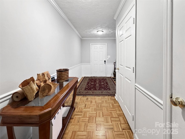 hallway featuring ornamental molding, light parquet flooring, and a textured ceiling