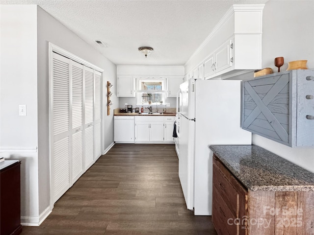 kitchen featuring white cabinetry, sink, dark stone countertops, dark hardwood / wood-style flooring, and white appliances