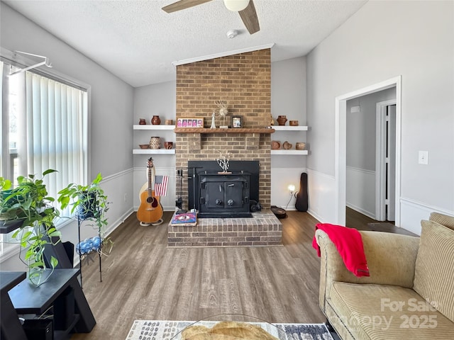 living room with lofted ceiling, hardwood / wood-style floors, a textured ceiling, and ceiling fan