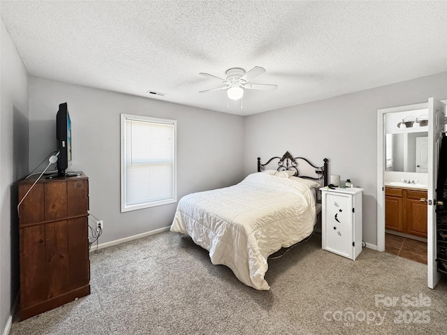 bedroom featuring connected bathroom, sink, carpet, ceiling fan, and a textured ceiling