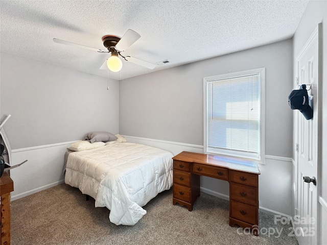 bedroom featuring light carpet, ceiling fan, and a textured ceiling