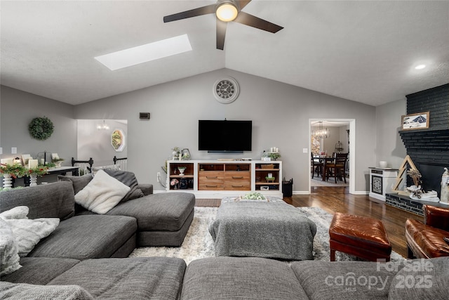 living room featuring hardwood / wood-style flooring, vaulted ceiling, ceiling fan with notable chandelier, and a fireplace