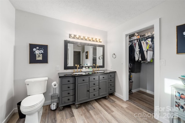 bathroom featuring hardwood / wood-style flooring, vanity, toilet, and a textured ceiling