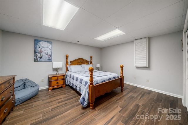 bedroom with dark wood-type flooring and a drop ceiling