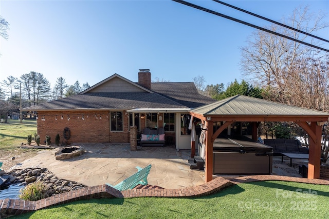 back of property featuring a gazebo, a hot tub, a patio, and a lawn