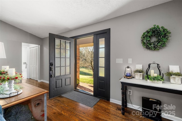 foyer featuring dark hardwood / wood-style floors, vaulted ceiling, and a textured ceiling