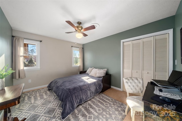 bedroom featuring multiple windows, a closet, ceiling fan, and carpet flooring