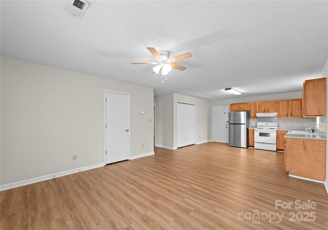 kitchen with sink, a textured ceiling, stainless steel fridge, electric stove, and light hardwood / wood-style floors