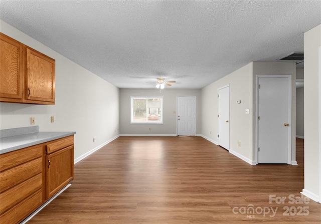 unfurnished living room with ceiling fan, light hardwood / wood-style flooring, and a textured ceiling