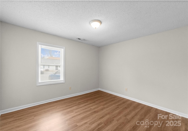 spare room with hardwood / wood-style floors and a textured ceiling