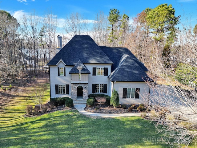 view of front of property with a shingled roof, a chimney, and a front yard