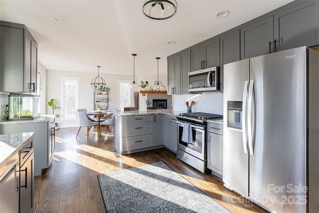 kitchen featuring gray cabinetry, light stone counters, tasteful backsplash, pendant lighting, and stainless steel appliances