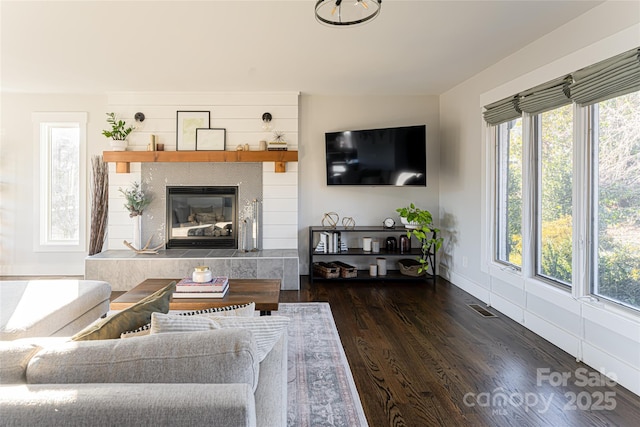 living room featuring dark hardwood / wood-style floors and a tiled fireplace