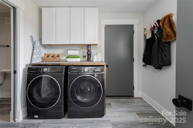 laundry area featuring washing machine and dryer and light hardwood / wood-style flooring