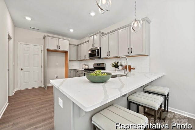 kitchen featuring gray cabinets, appliances with stainless steel finishes, sink, hanging light fixtures, and kitchen peninsula