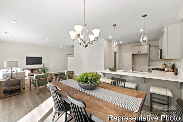 dining room with a chandelier, sink, and light wood-type flooring