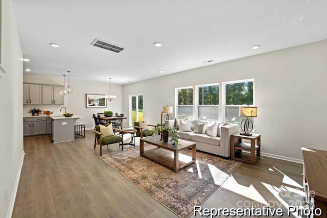 living room featuring an inviting chandelier, wood-type flooring, and sink