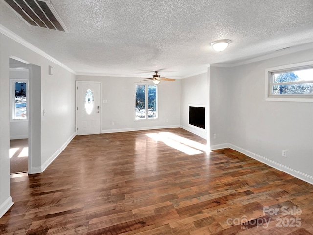 unfurnished living room featuring ceiling fan, ornamental molding, dark hardwood / wood-style flooring, and a wealth of natural light