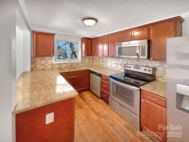 kitchen featuring appliances with stainless steel finishes, sink, backsplash, and light hardwood / wood-style flooring