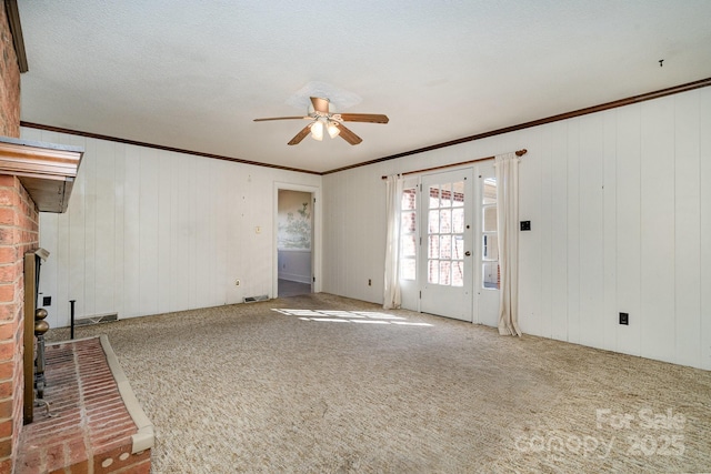 unfurnished living room featuring ornamental molding, carpet floors, a fireplace, and ceiling fan