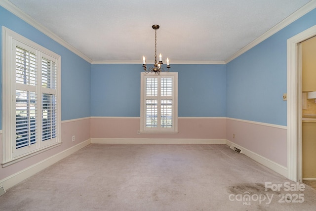 carpeted spare room featuring ornamental molding and a chandelier