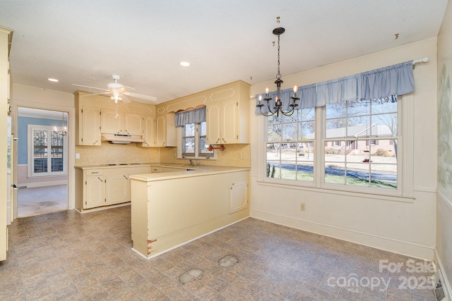 kitchen with sink, hanging light fixtures, kitchen peninsula, decorative backsplash, and cooktop