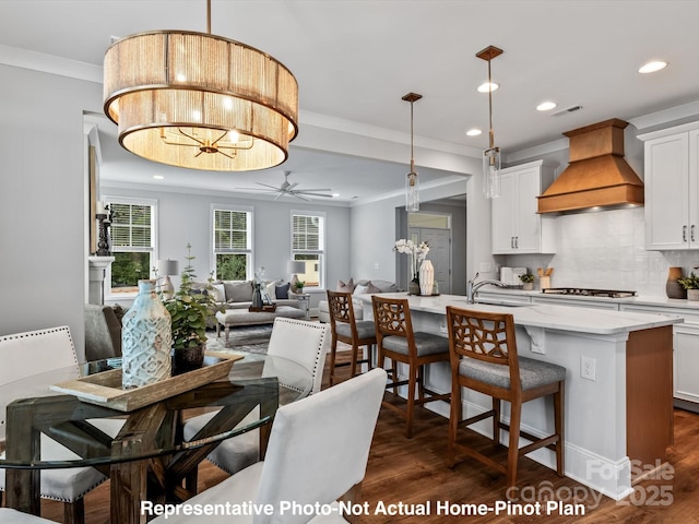 dining room featuring dark hardwood / wood-style flooring, sink, ceiling fan with notable chandelier, and ornamental molding