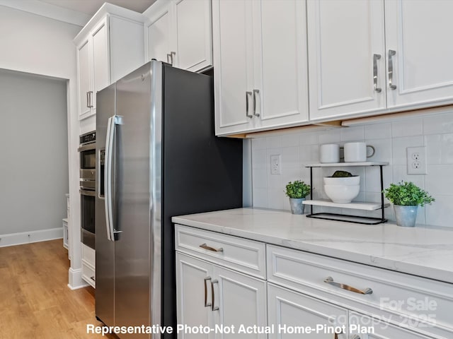 kitchen featuring white cabinetry, light stone counters, and backsplash