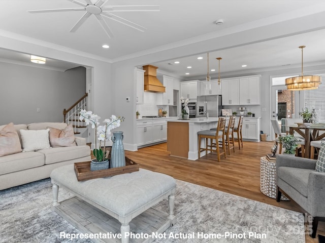 living room featuring an inviting chandelier, crown molding, and light wood-type flooring