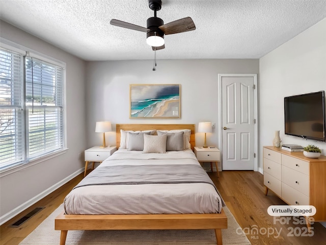 bedroom featuring hardwood / wood-style floors, a textured ceiling, and ceiling fan