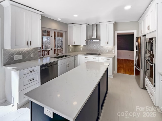 kitchen with appliances with stainless steel finishes, white cabinetry, sink, light stone countertops, and wall chimney exhaust hood